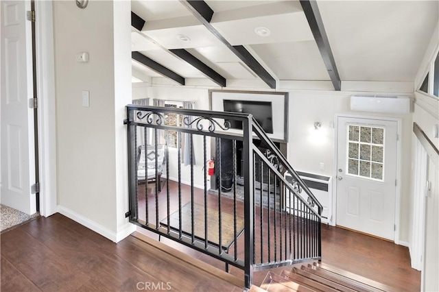 stairway with beam ceiling, a wall mounted air conditioner, and hardwood / wood-style flooring