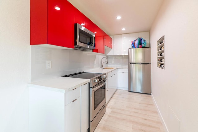 kitchen featuring sink, decorative backsplash, light hardwood / wood-style floors, white cabinetry, and stainless steel appliances