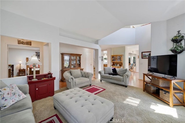 carpeted living room with high vaulted ceiling