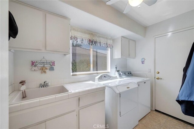 clothes washing area with ceiling fan, sink, cabinets, washer and clothes dryer, and light tile patterned flooring