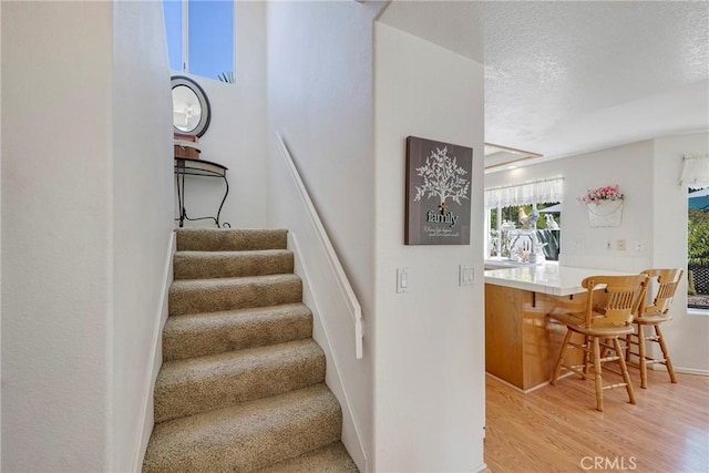 staircase with a textured ceiling and wood finished floors