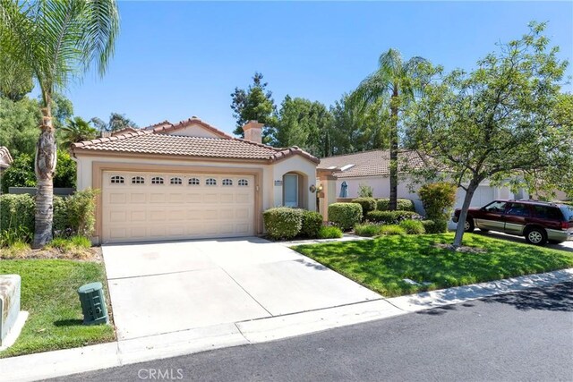 mediterranean / spanish-style home featuring a garage and a front lawn