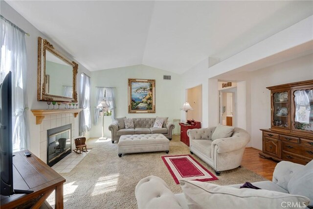 living room with a tiled fireplace and vaulted ceiling