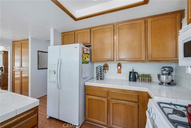 kitchen with tile counters, light hardwood / wood-style floors, and white appliances