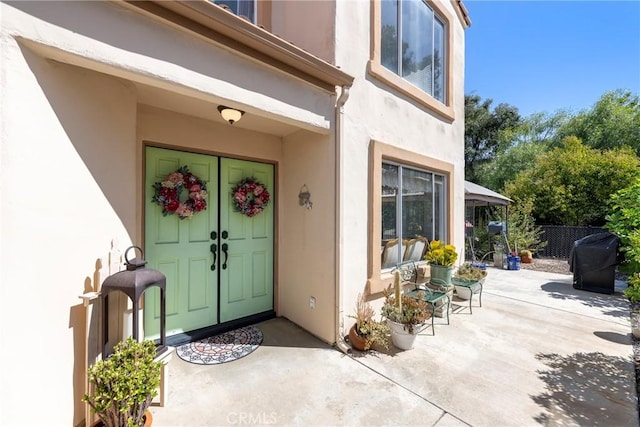 doorway to property featuring a patio area, fence, and stucco siding