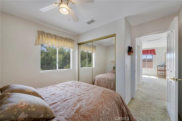 bedroom with ceiling fan, light carpet, and a closet