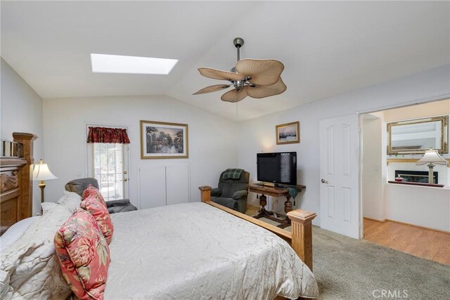 bedroom featuring vaulted ceiling with skylight, ceiling fan, and hardwood / wood-style floors