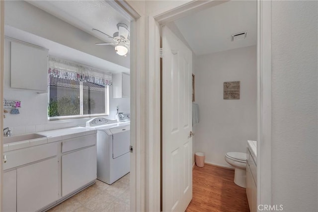 bathroom with visible vents, toilet, a ceiling fan, wood finished floors, and independent washer and dryer