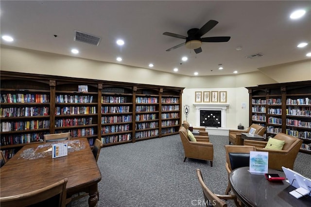 sitting room with wall of books, carpet, and visible vents