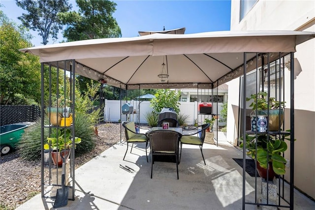 view of patio featuring outdoor dining space, fence, and a gazebo