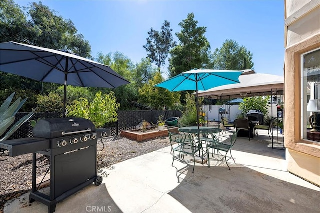 view of patio featuring a garden, a grill, fence, outdoor dining area, and a gazebo