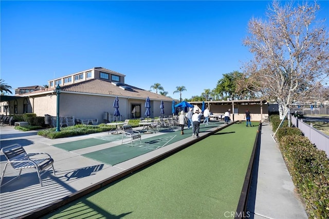 view of property's community with shuffleboard and fence