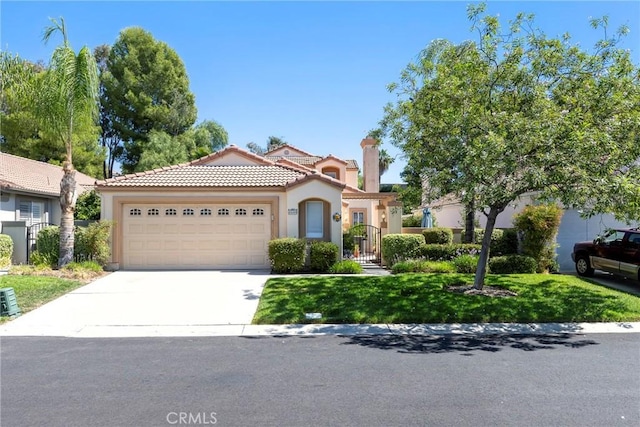 mediterranean / spanish-style home with concrete driveway, stucco siding, a tile roof, an attached garage, and a front yard