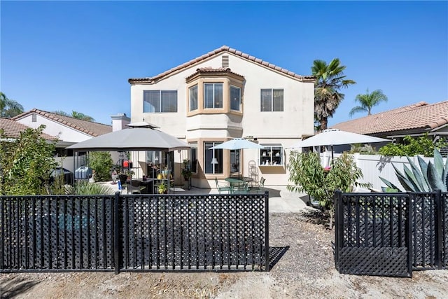 back of house with fence, a patio, a gazebo, and stucco siding