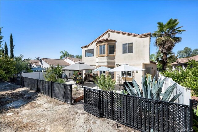 view of front facade with a gazebo, a patio, a fenced backyard, and stucco siding