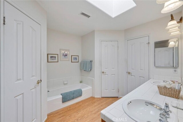 bathroom featuring wood-type flooring, vanity, and a tub