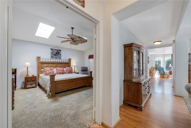 bedroom with light colored carpet, lofted ceiling with skylight, and ceiling fan