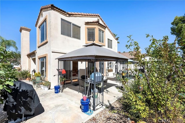 rear view of house with a gazebo, a patio area, and stucco siding