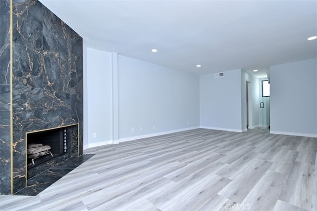 unfurnished living room featuring light wood-type flooring and a tile fireplace