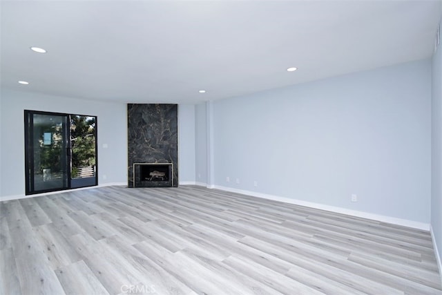 unfurnished living room with a premium fireplace and light hardwood / wood-style floors