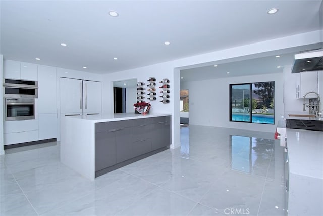 kitchen featuring double oven, white cabinetry, and sink