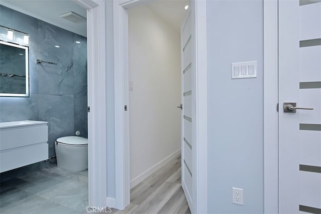 bathroom featuring hardwood / wood-style floors, vanity, toilet, and tile walls