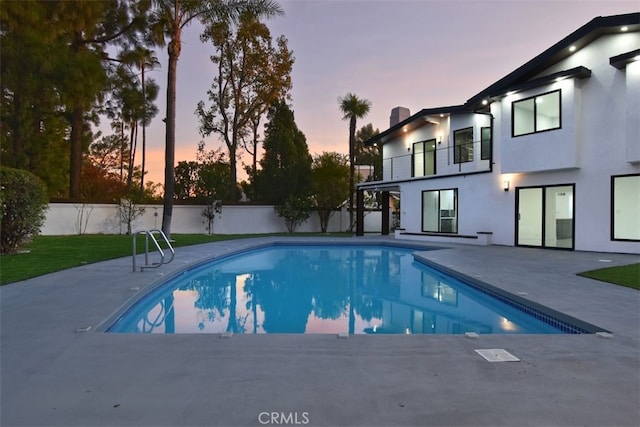 pool at dusk featuring a patio