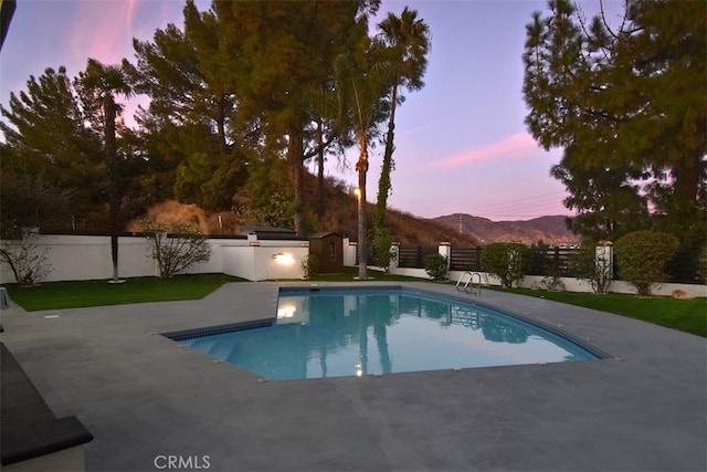 pool at dusk with a mountain view and a patio area