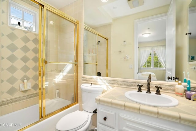 full bathroom featuring vanity, toilet, and bath / shower combo with glass door