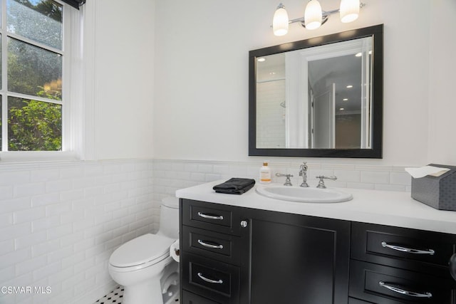 bathroom with tile patterned floors, vanity, toilet, and tile walls