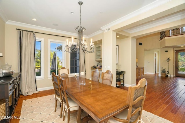 dining space featuring light hardwood / wood-style floors, ornamental molding, and a notable chandelier