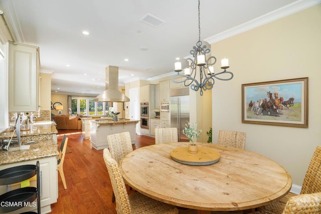 dining area featuring sink, an inviting chandelier, light hardwood / wood-style floors, and ornamental molding