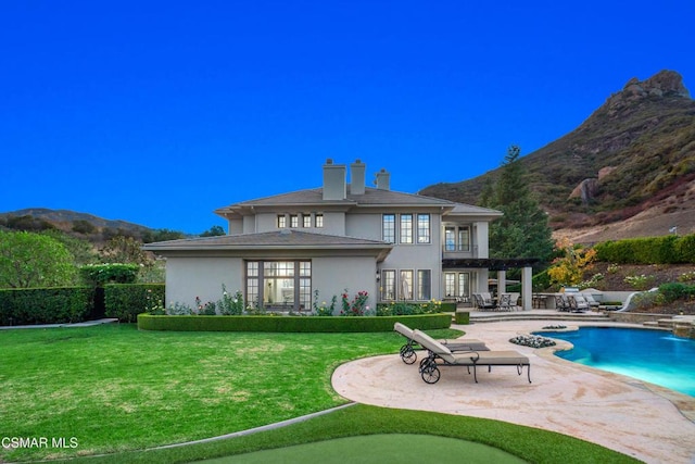 back of house featuring a lawn, a mountain view, a patio, and a fenced in pool