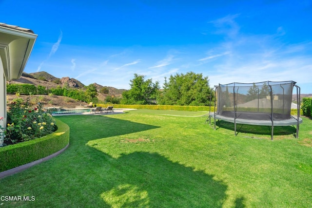 view of yard with a mountain view, a trampoline, a pool, and a patio area