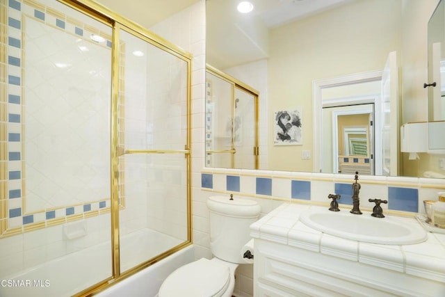 full bathroom with combined bath / shower with glass door, vanity, and toilet