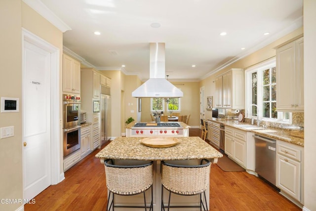 kitchen with light stone countertops, island range hood, stainless steel appliances, and light hardwood / wood-style floors