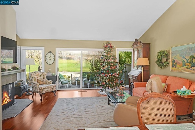 living room featuring a tile fireplace, wood-type flooring, and high vaulted ceiling