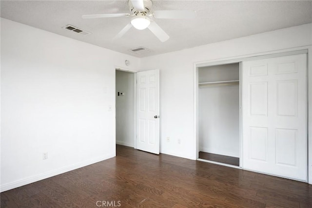 unfurnished bedroom with ceiling fan, dark hardwood / wood-style flooring, and a closet