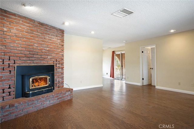 unfurnished living room featuring a large fireplace, dark hardwood / wood-style flooring, and a textured ceiling