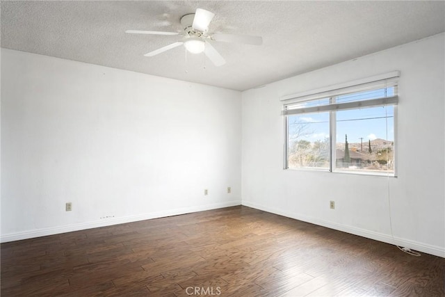 empty room featuring ceiling fan, dark wood-type flooring, and a textured ceiling