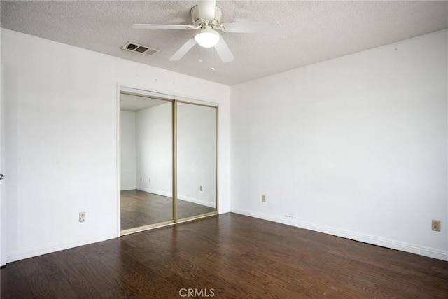 unfurnished bedroom with ceiling fan, dark hardwood / wood-style floors, a textured ceiling, and a closet