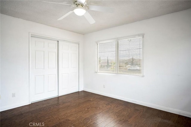 unfurnished bedroom with ceiling fan, a closet, dark wood-type flooring, and a textured ceiling