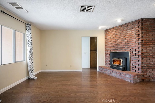 unfurnished living room featuring a textured ceiling, dark hardwood / wood-style flooring, and a wood stove