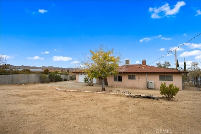 back of property with central AC unit and a garage