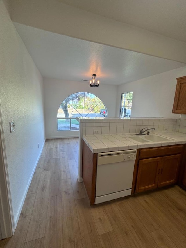 kitchen featuring sink, dishwasher, tile countertops, and a healthy amount of sunlight