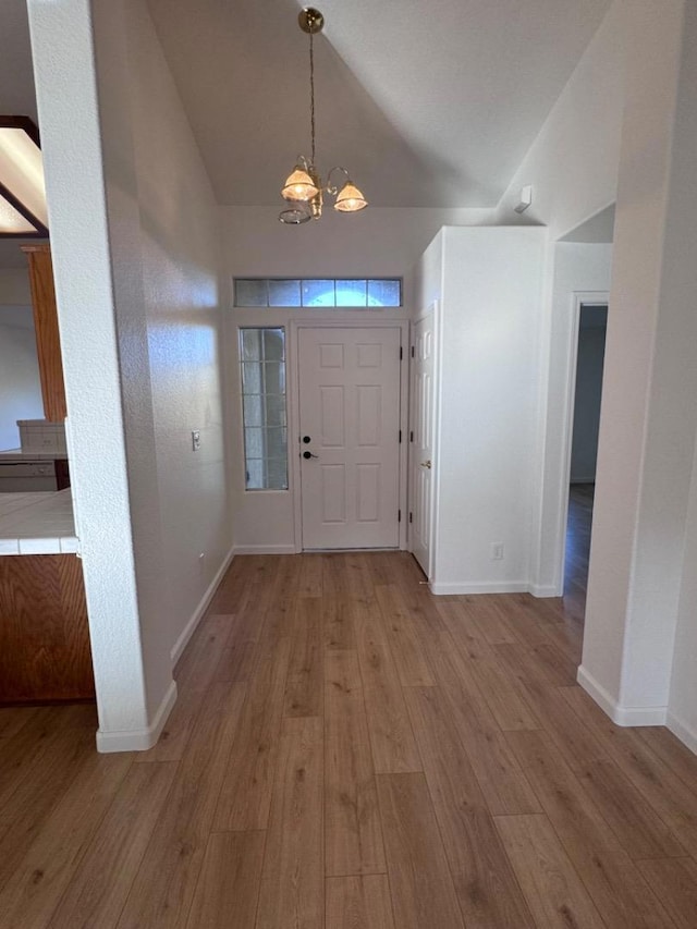 foyer entrance featuring light hardwood / wood-style floors, a chandelier, and vaulted ceiling