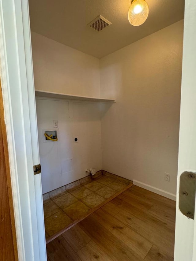 clothes washing area with wood-type flooring, hookup for an electric dryer, and hookup for a washing machine