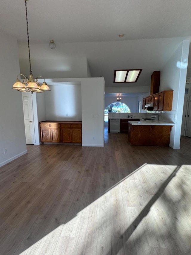 kitchen with lofted ceiling, dark hardwood / wood-style flooring, hanging light fixtures, kitchen peninsula, and a chandelier