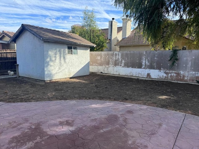 view of side of home with a storage unit and a patio area