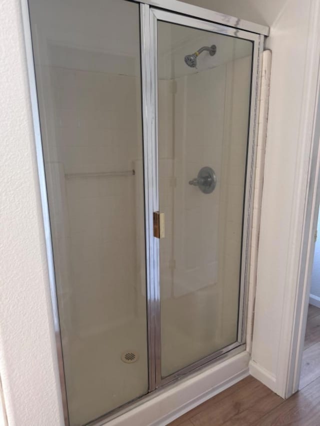 bathroom with wood-type flooring and a shower with door